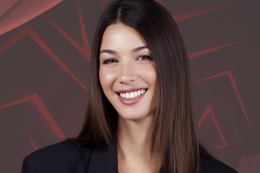 Ginevra in giacca nera, sorride su un fondo rosso